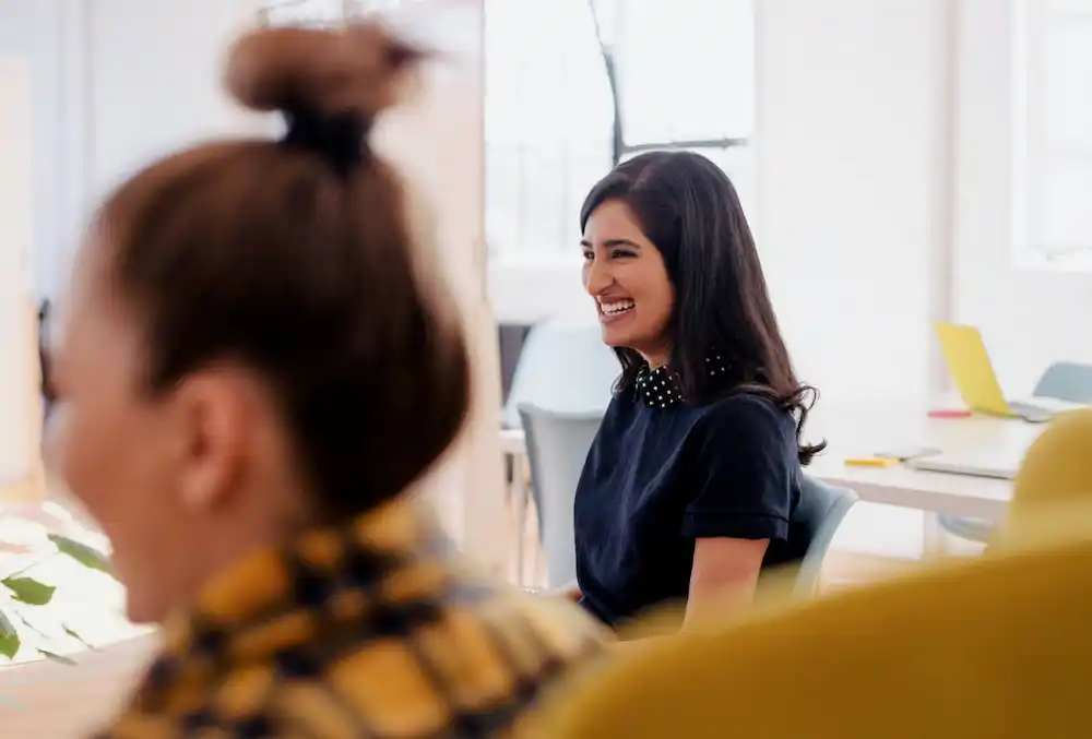 Jeune femme souriante au sein d'une équipe de collaboration d'entreprise