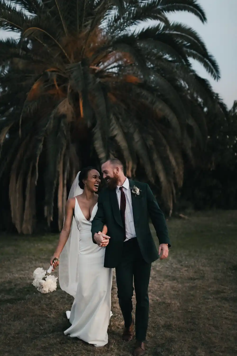 Un couple de jeune mariés heureux sous un palmier