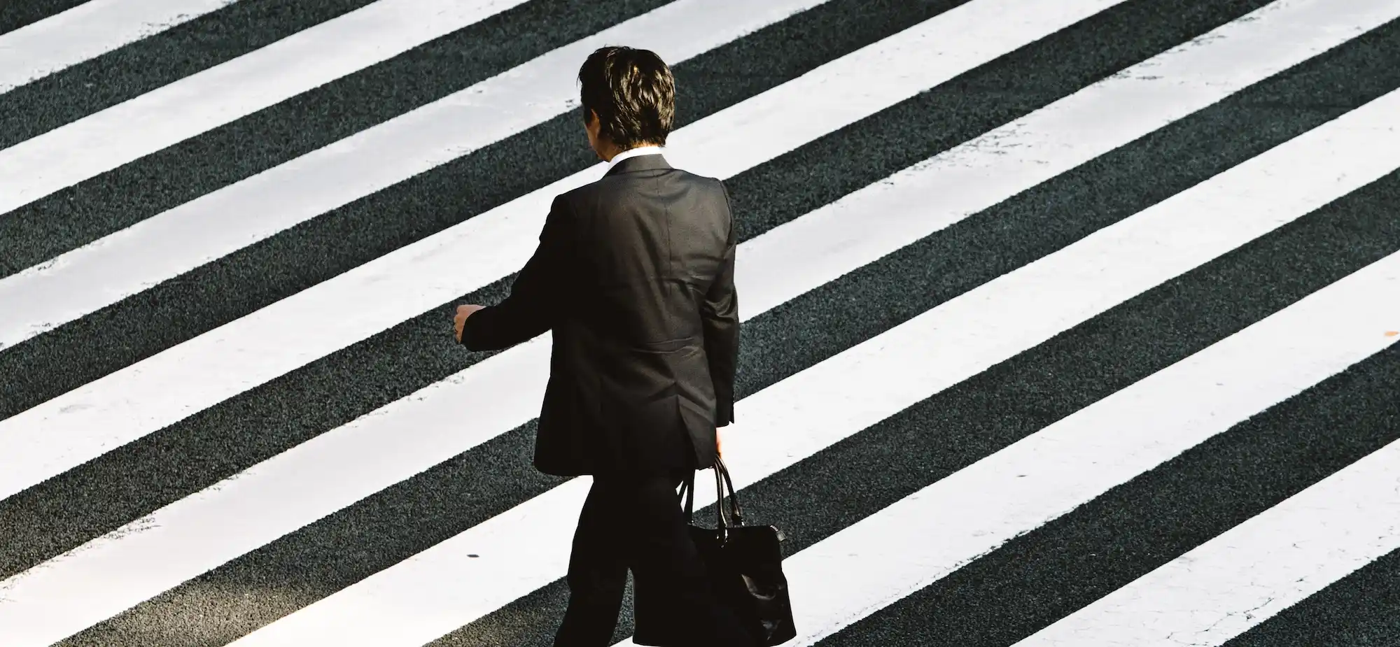 Un homme d'affaires en costume traversant un passage piéton noir et blanc